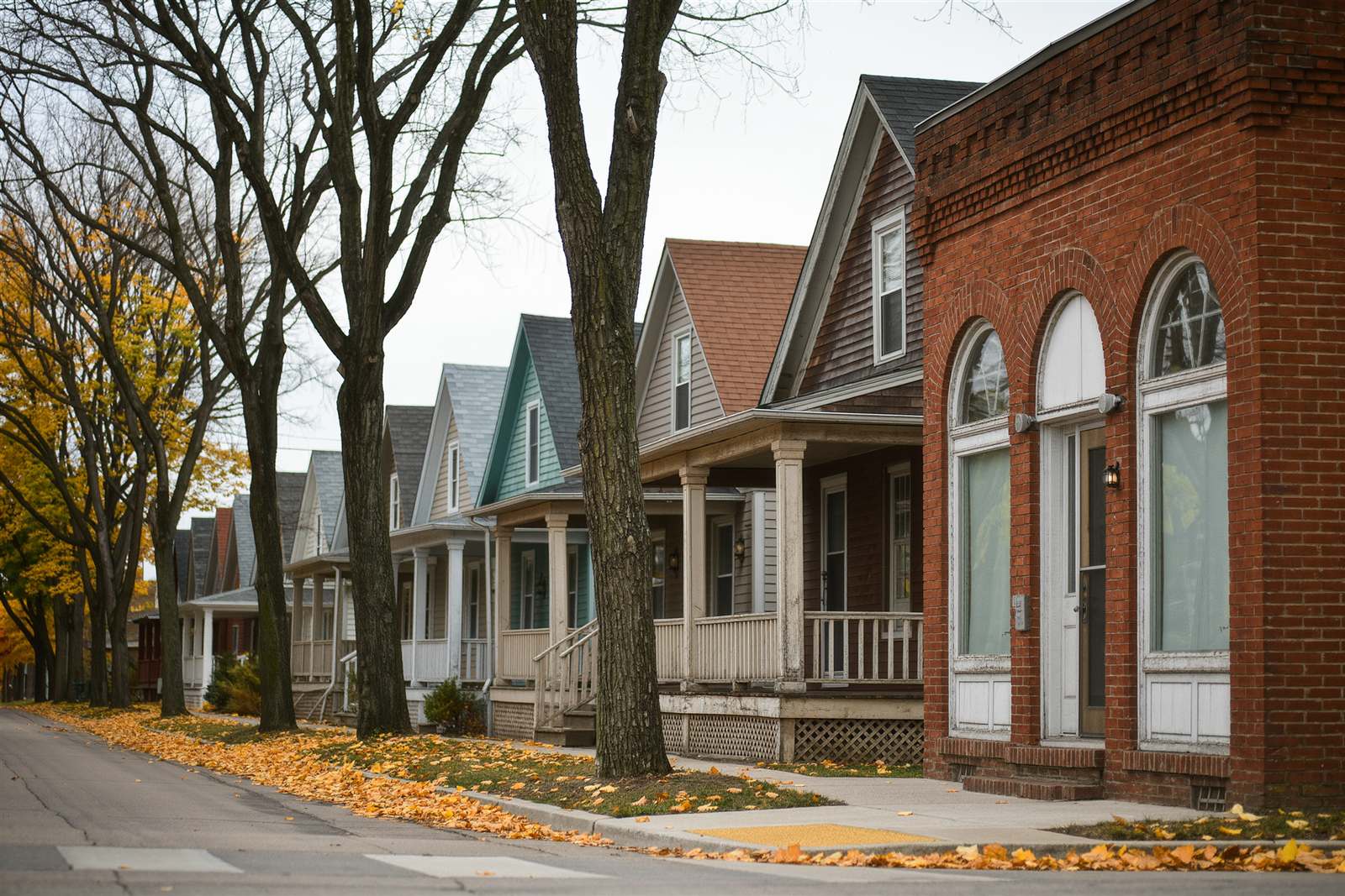 A tree-lined residential street in south Minneapolis in autumn with older houses and a brick corner building