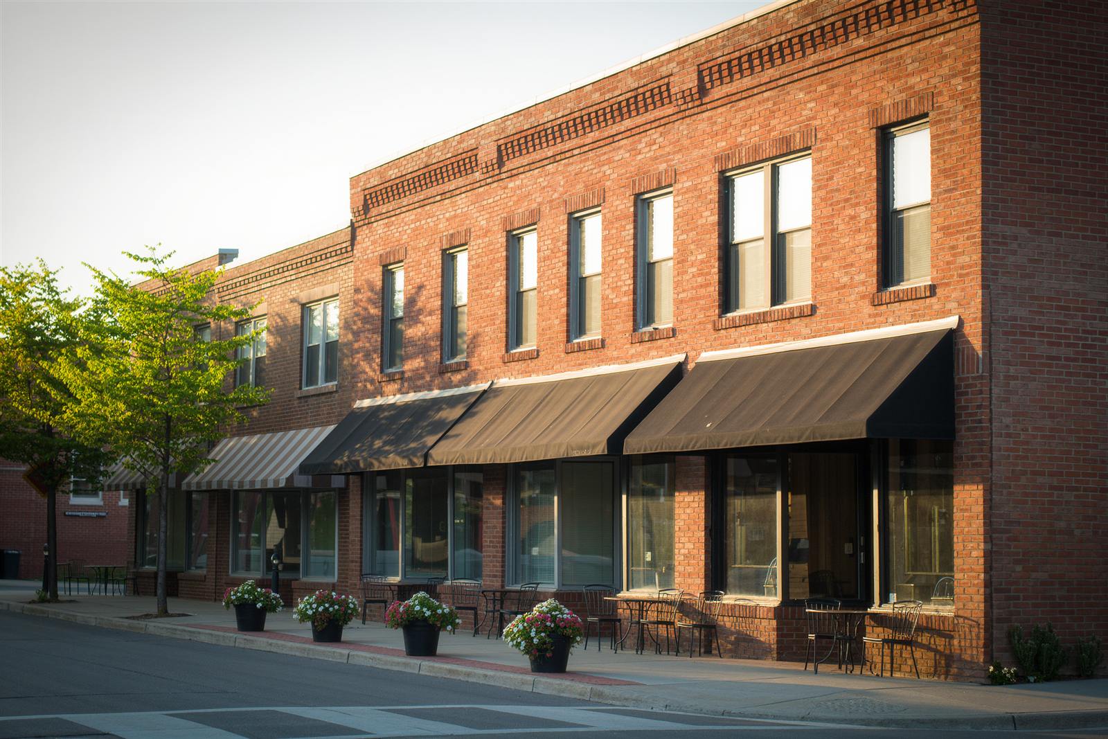 A neighborhood street of brick storefronts with awnings and cafe tables in Minneapolis